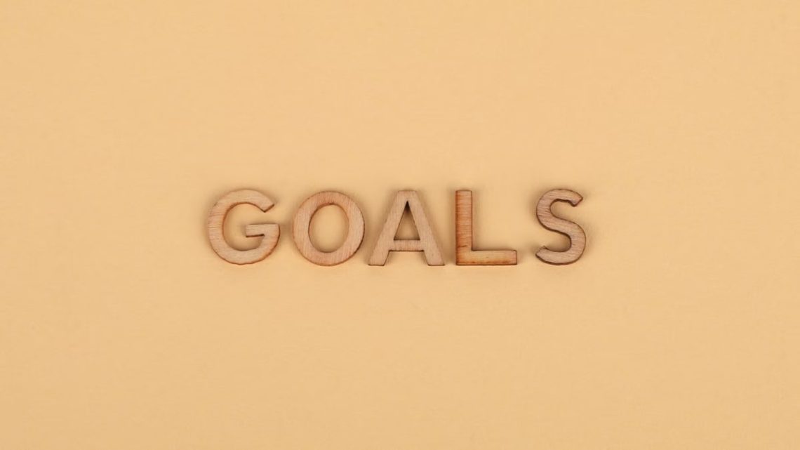 Wooden letters spelling 'GOALS' on a plain background, emphasizing motivation.