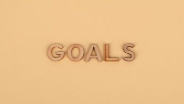 Wooden letters spelling 'GOALS' on a plain background, emphasizing motivation.