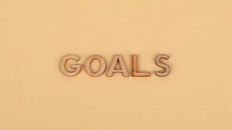 Wooden letters spelling 'GOALS' on a plain background, emphasizing motivation.